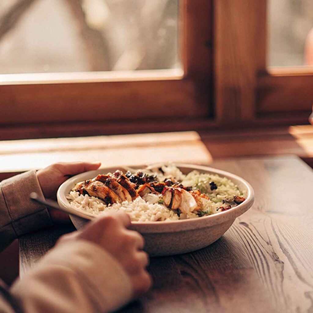 Woman in a cozy kitchen examining her chipotle bowl with a curious expression