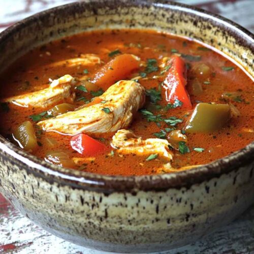 A rustic bowl of Cajun chicken soup with garnish