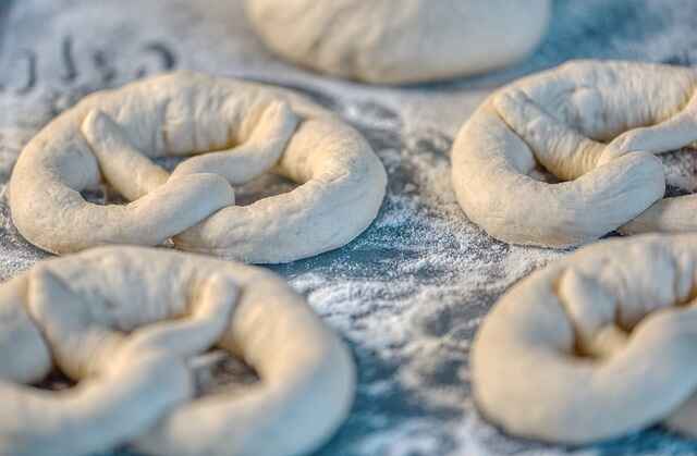 Unbaked pretzel shapes resting on a floured wooden counter