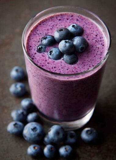Creamy blueberry yogurt smoothie served in a glass, topped with fresh blueberries and smooth blended texture