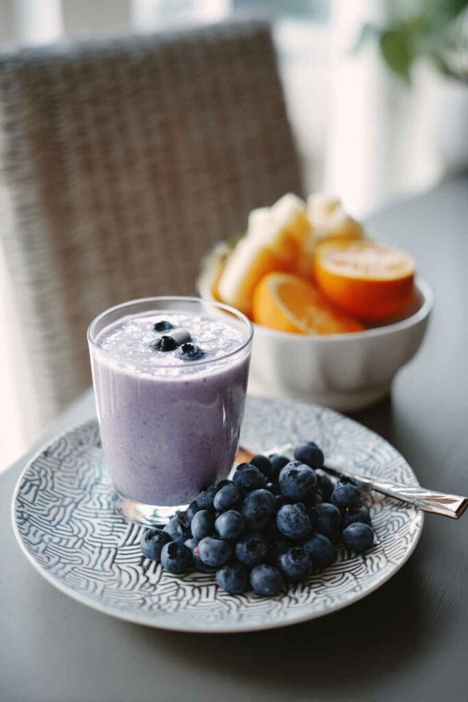 Blueberry yogurt smoothie served in a glass with fresh blueberries at the end of the recipe