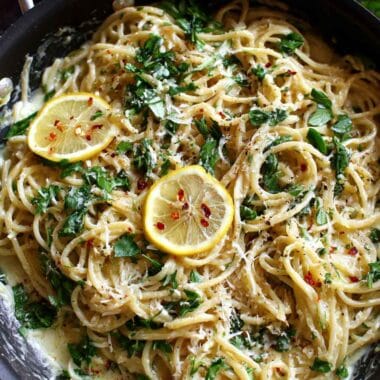 Creamy lemon parmesan pasta with fresh herbs and grated cheese in a pan