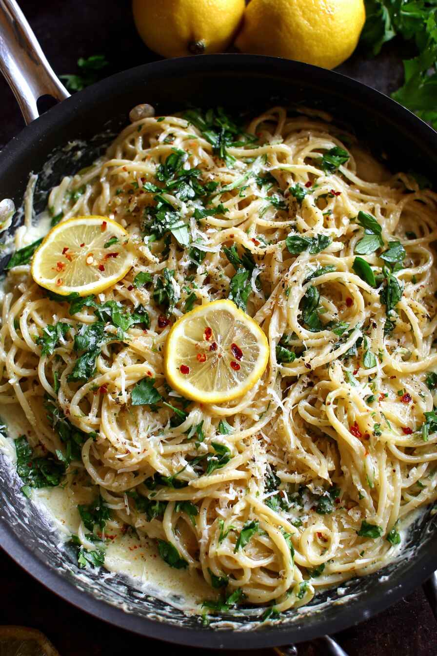 Creamy lemon parmesan pasta with fresh herbs and grated cheese in a pan
