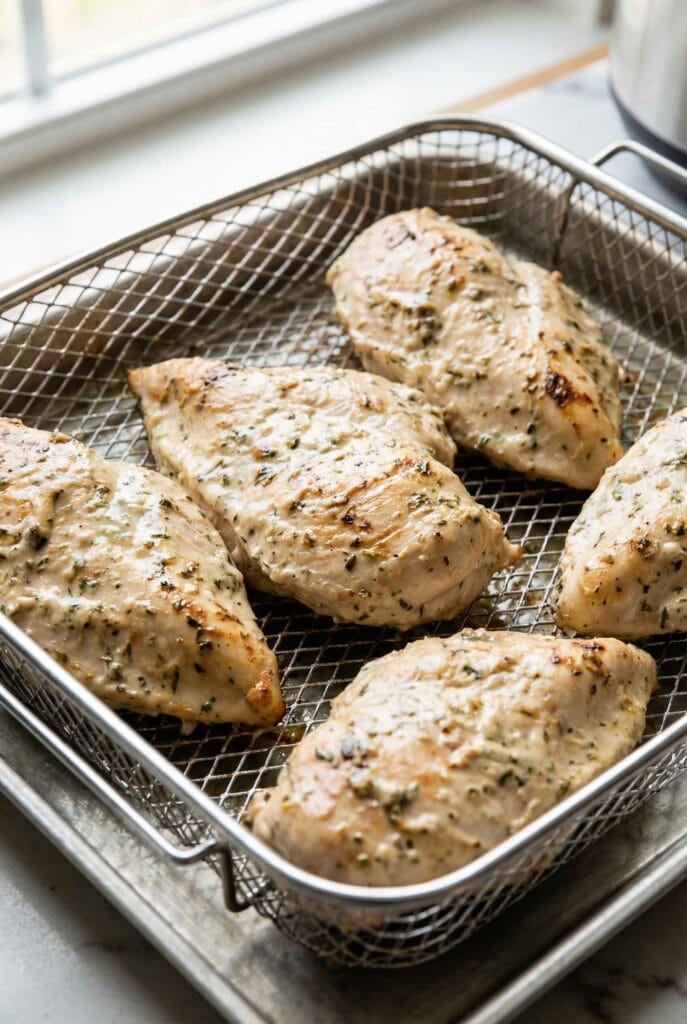 Yogurt marinated chicken breast cooking in an air fryer basket