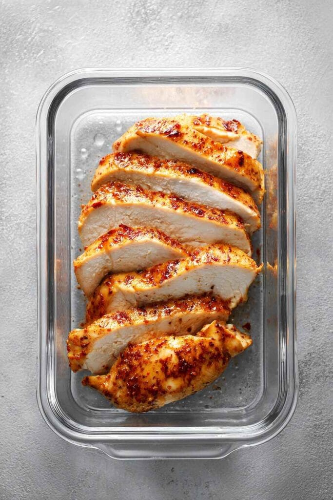 Stored yogurt marinated chicken breast slices in an airtight glass container