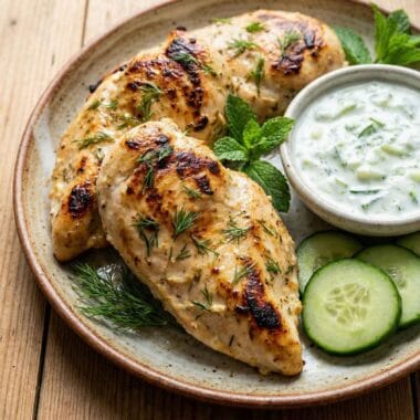Yogurt marinated chicken breast served with cucumber yogurt sauce and fresh herbs