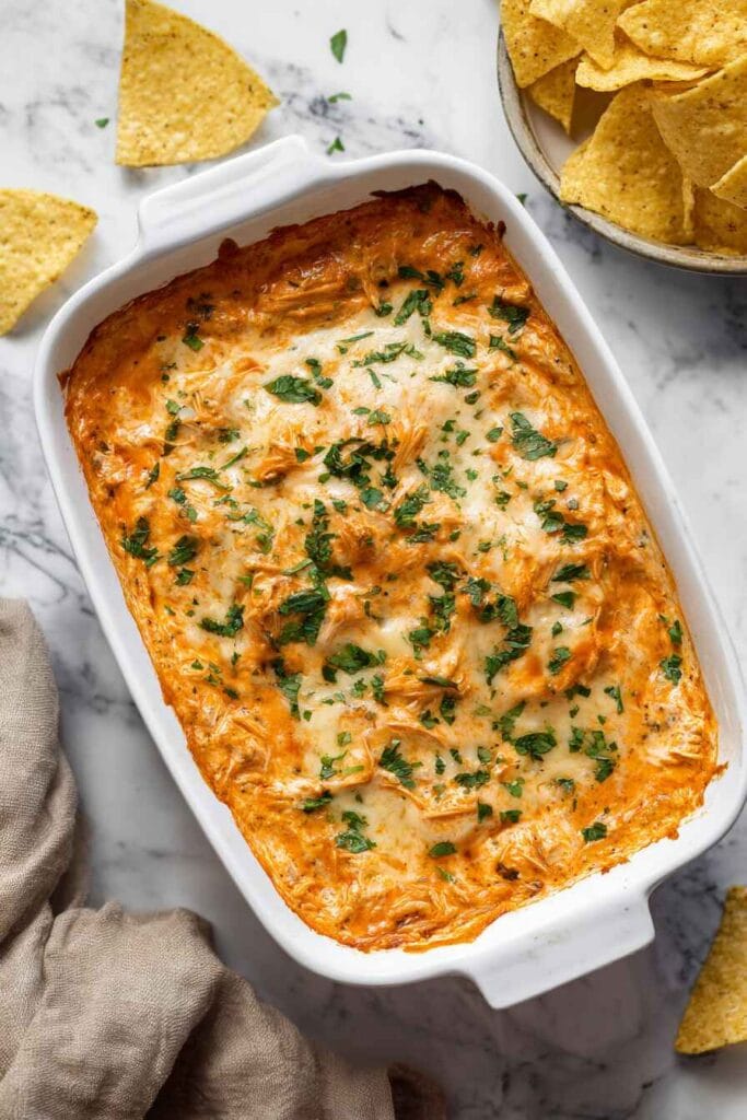 baked high protein buffalo chicken dip with melted cheese in a casserole dish