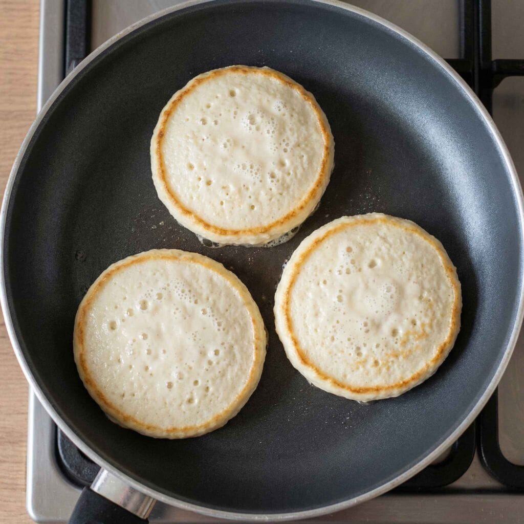 cottage cheese pancake cooking in a pan with bubbles forming
