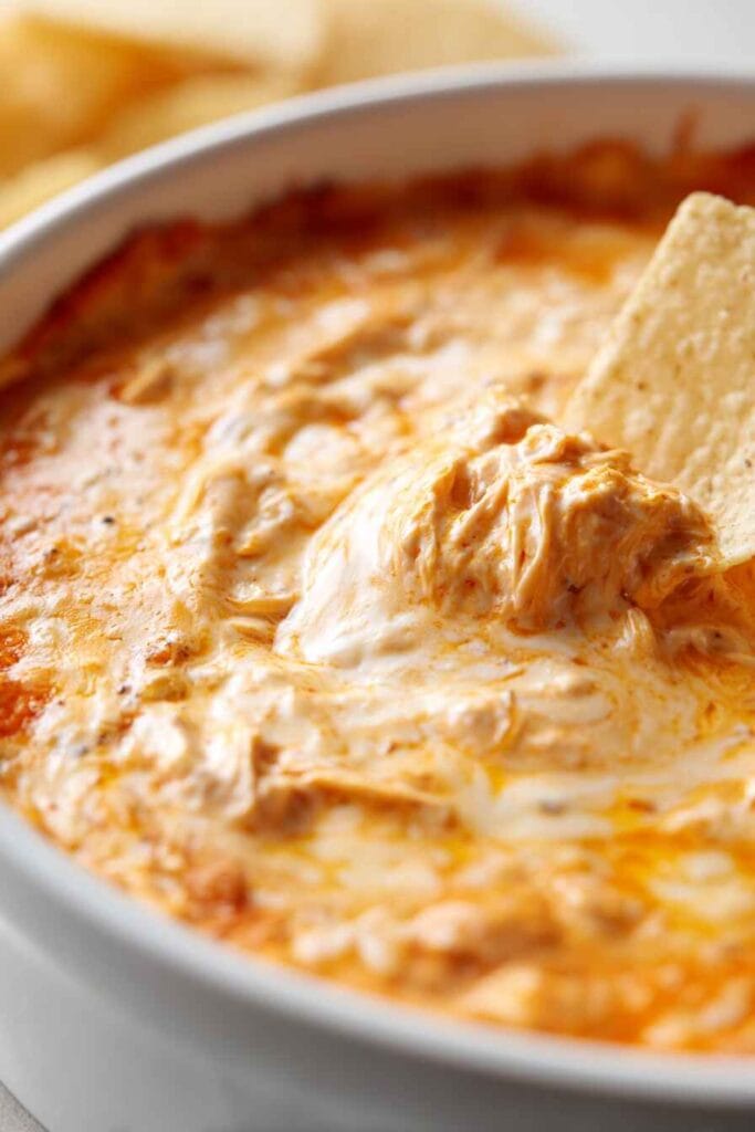 creamy high protein buffalo chicken dip with melted cheese and tortilla chip