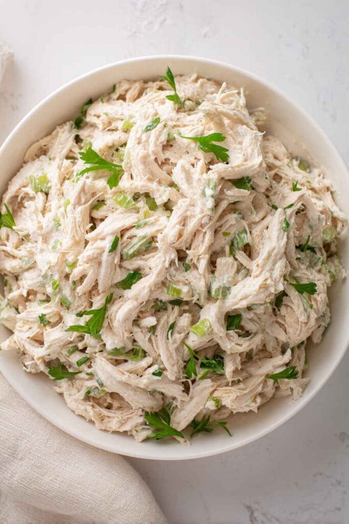 finished high protein chicken salad in a bowl with shredded chicken and fresh herbs