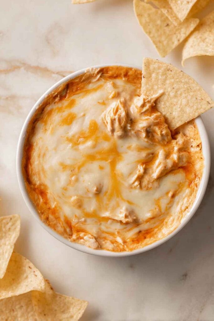 high protein buffalo chicken dip with melted cheese served with tortilla chips