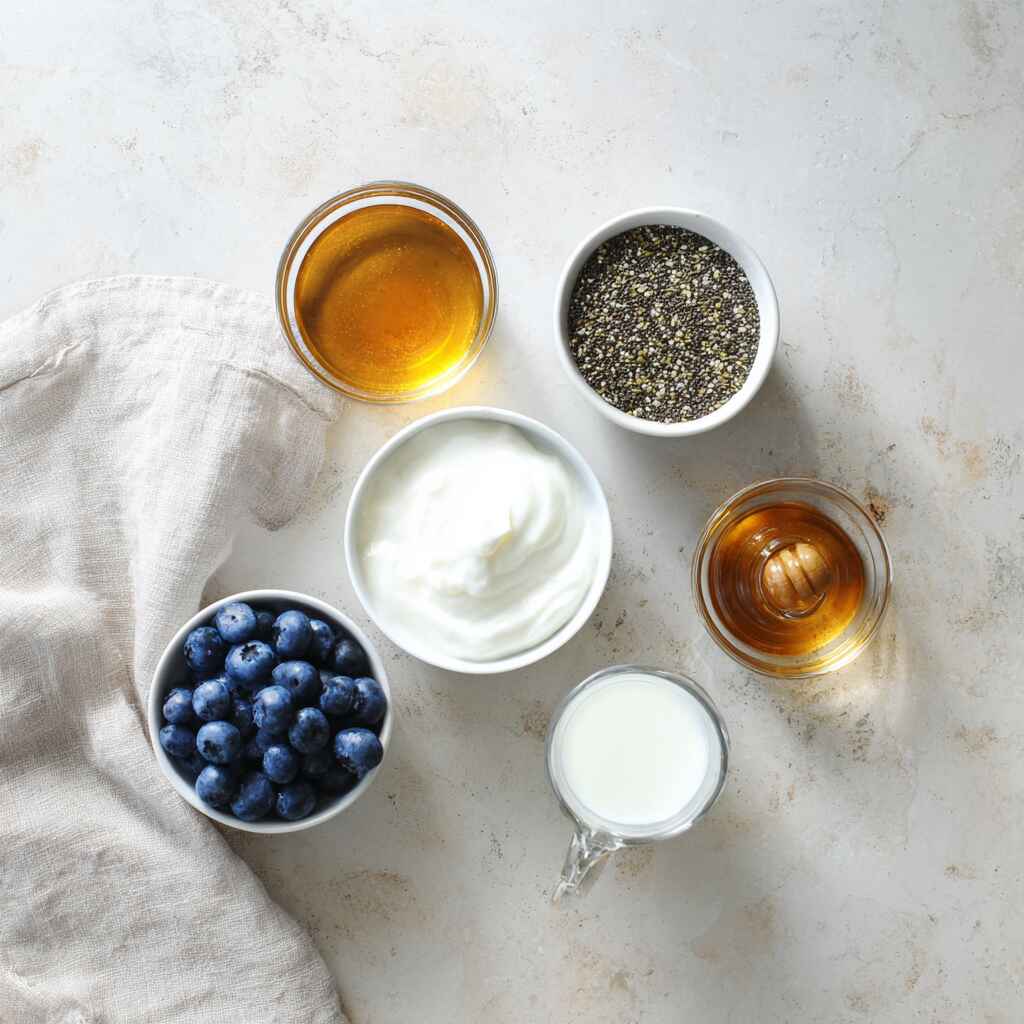 ingredients for greek yogurt chia seed pudding including yogurt chia seeds milk honey and blueberries
