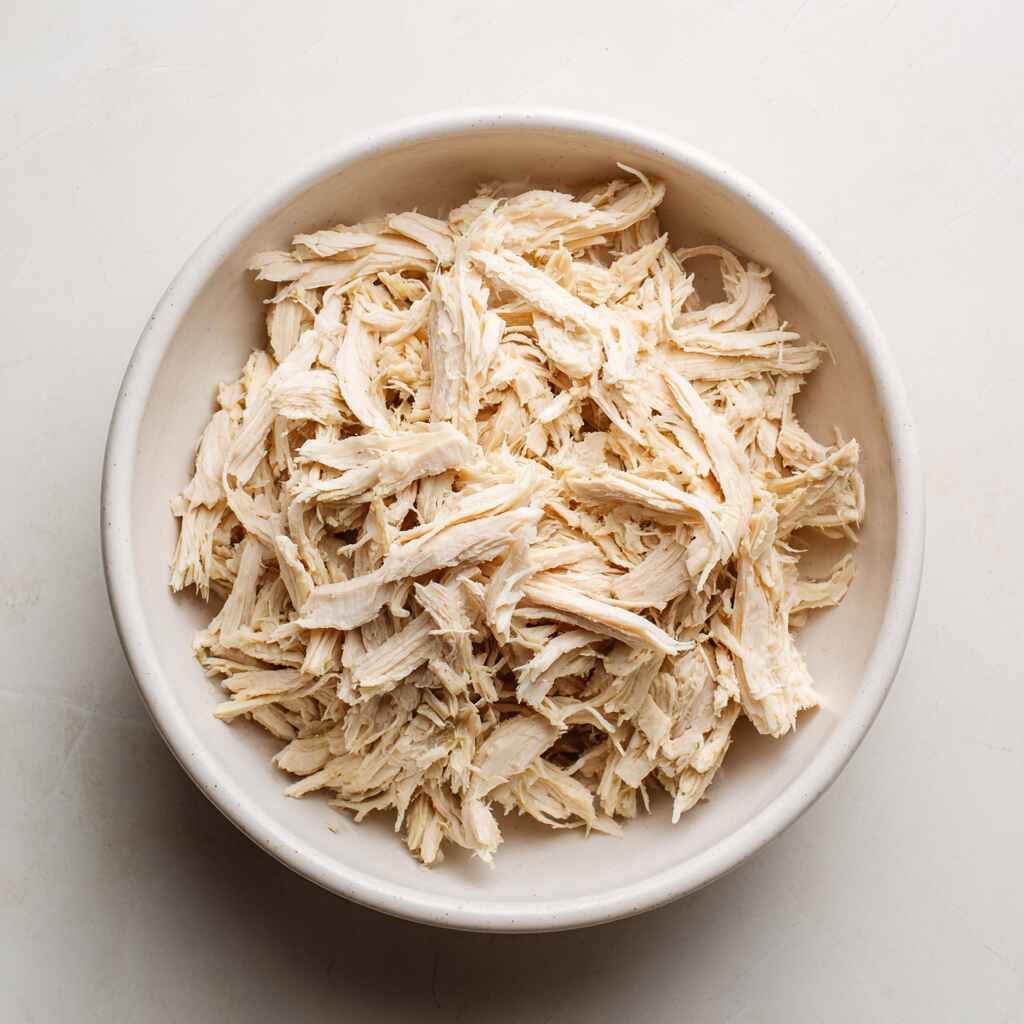 shredded cooked chicken in a bowl for high protein chicken salad preparation