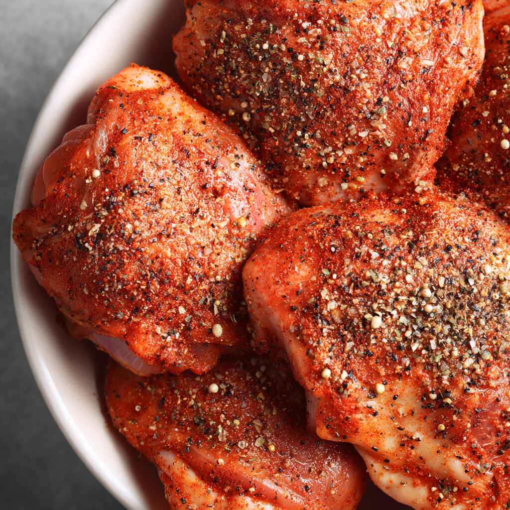seasoned raw chicken thighs coated with paprika, garlic, salt, and black pepper