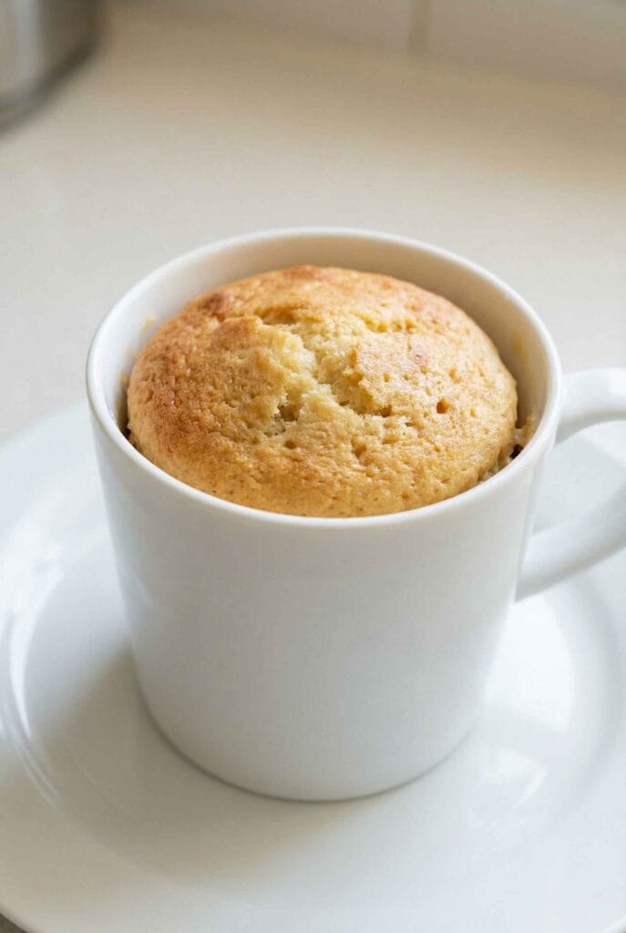 finished high protein mug cake in white mug soft golden top