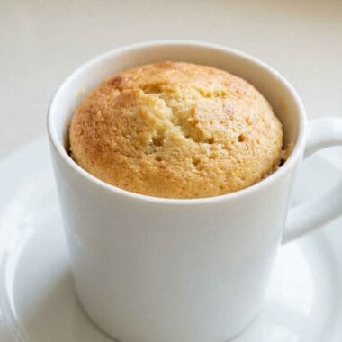 High protein vanilla mug cake in a white mug, soft fluffy texture, easy 3 ingredient recipe