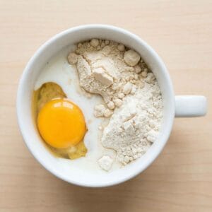 Egg, milk, and light protein powder in a mug before mixing